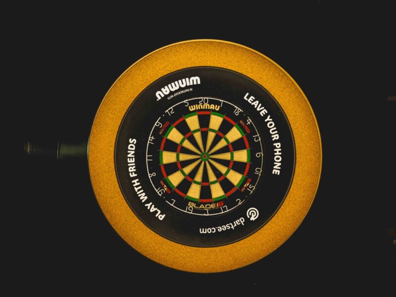 Cible de fléchettes Winmau avec surround doré installée dans un bar à Morzine, réalisation électrique Bernard Braize